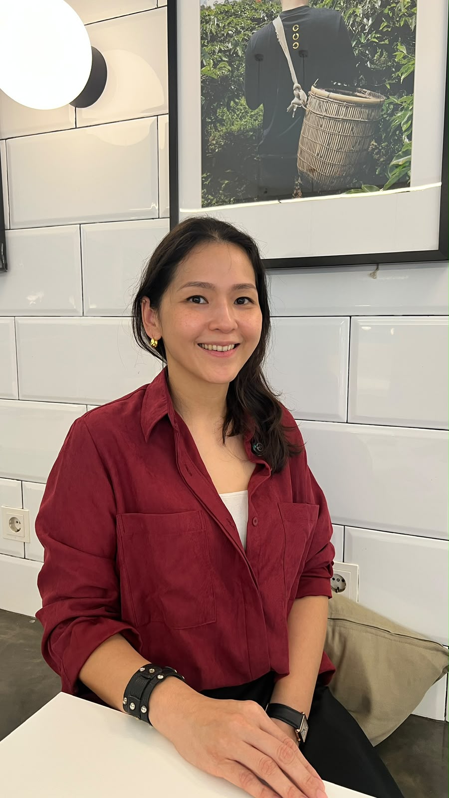 Yulianti Gunawan tersenyum sambil duduk mengenakan kemeja merah.